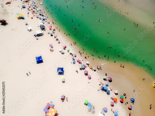  Aerial view of paradisiac beach with white sand, green sea and colorful umbrella.