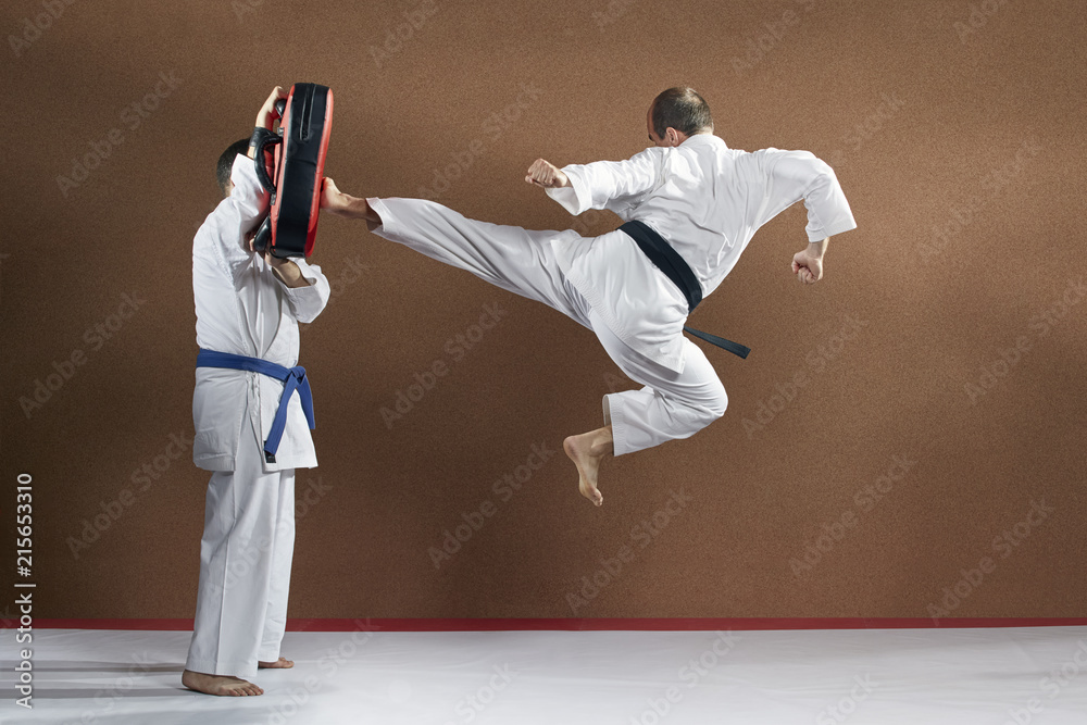 On the simulator, an adult athlete trains a kick in a jump