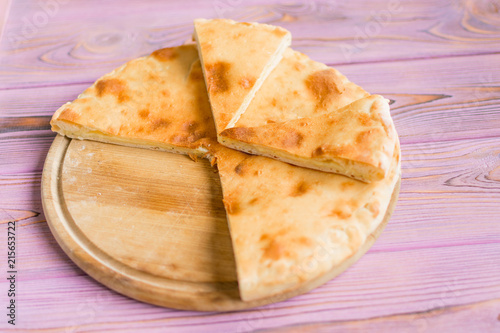 Pie with cheese on a wooden pink background. Khachapuri - flat cake with cheese.