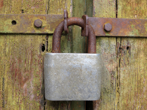 Old rusty padlock on the locked wooden doors. Vintage gate, home security concept