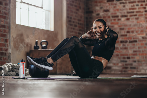 Smiling female in the gym doing sit-up photo