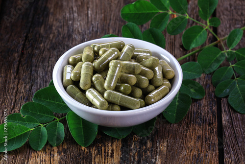 Herbal capsules from moringa leaf in white cup