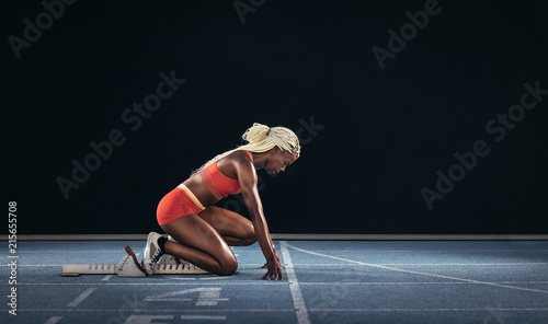 Woman sprinter using a starting block to start her sprint on a r