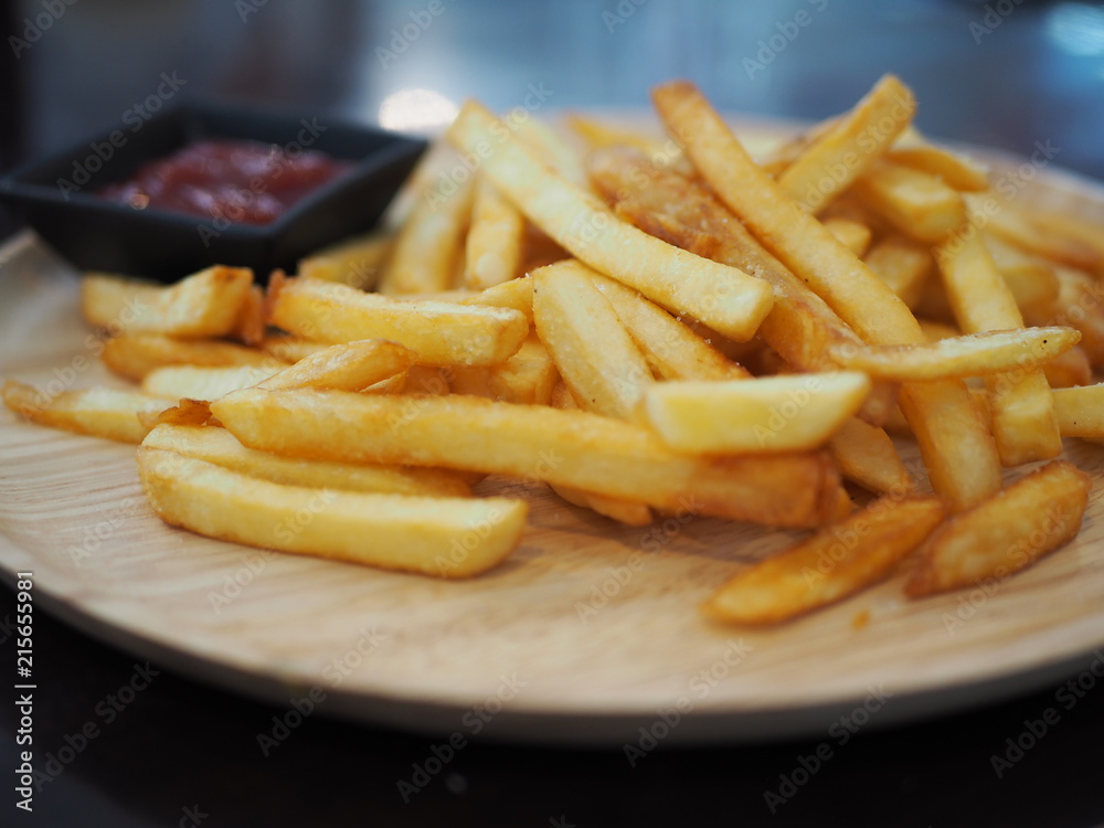 Fresh fried french fries with ketchup on wooden dish