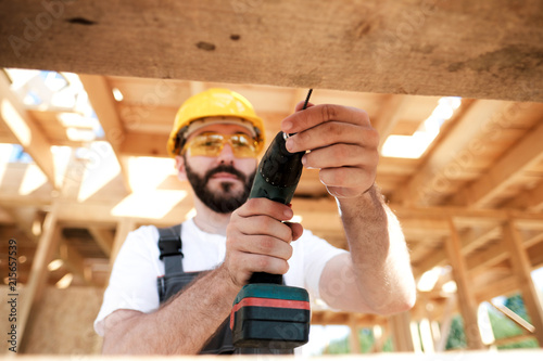 The man is a builder on the roof of a wooden frame house. photo