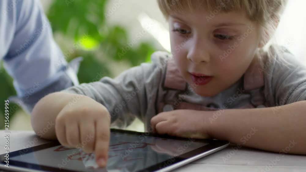 Cute little girl drawing on touchscreen of digital tablet with elder brother at home Cute little girl drawing on touchscreen of digital tablet with elder brother at home