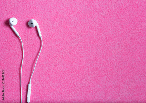 White modern earphones on the pink cloth background
