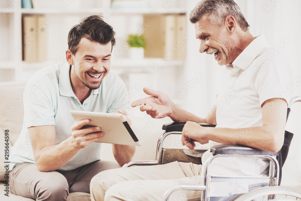 Laughing Young Son Showing Tablet to Father. Laughing Young Son Showing Tablet to Father.