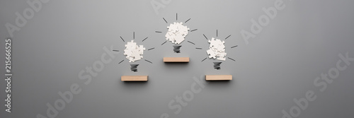 Fotografía Wide panorama view of three light bulb formed by white puzzle pieces placed on w
