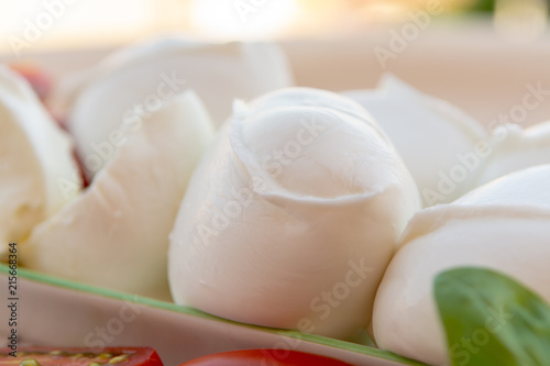 Fresh soft Italian white cheese mozzarella buffalo, original from Campania, Paestrum and Foggia regions, South Italy, served with tomatoes and fresh basil