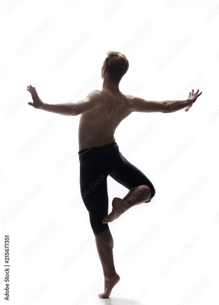 rear view, one young man back, ballet dancer, posing arms outstretched, standing on one leg in air, white background, photo shoot.