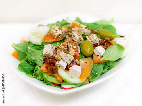 Fresh summer salad with cooked tuna fish chops, lettuce, green radicchio, frresh tomatoes, dry tomatoes, cucumbers, green olives and various seeds