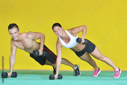 Beautiful fitness young sporty couple doing push ups together indoors.