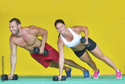 Beautiful fitness young sporty couple doing push ups together indoors. © blicsejo