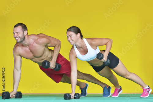 Beautiful fitness young sporty couple doing push ups together indoors.