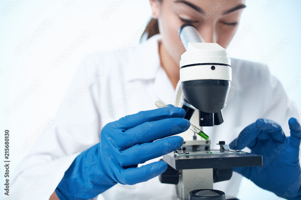 woman looking through a microscope in a laboratory woman looking through a microscope in a laboratory