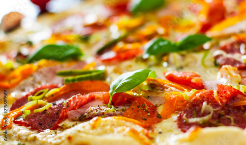 Pizza with Mozzarella cheese, Ham, Tomatoes, salami, pepper, pepperoni Spices and Fresh Basil. Italian pizza. Close up.
