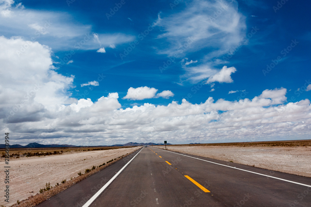 Ruta en desierto con cielo nuboso