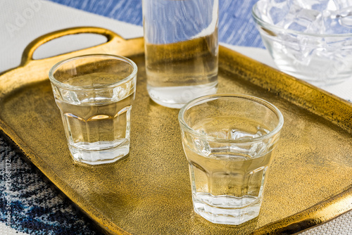 Glasses and bottle of traditional drink Ouzo or Raki on bronze dish photo