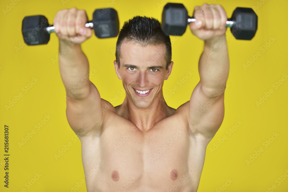 Strong attractive man performs exercises using a resistance band. Photo of muscular male isolated on yellow background. Strength and motivation Strong attractive man performs exercises using a resistance band. Photo of muscular male isolated on yellow background. Strength and motivation