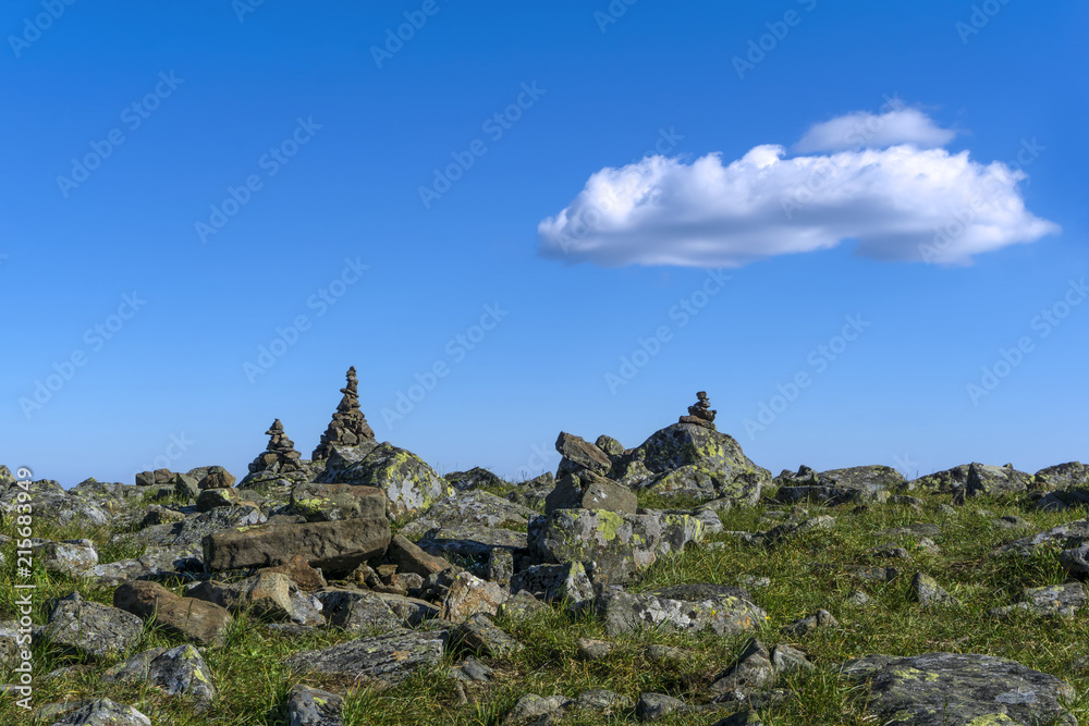 bright landscape of a high-altitude plateau with folded travelers pyramids cairns of stones under a blue sky with clouds.. bright landscape of a high-altitude plateau with folded travelers pyramids cairns of stones under a blue sky with clouds..
