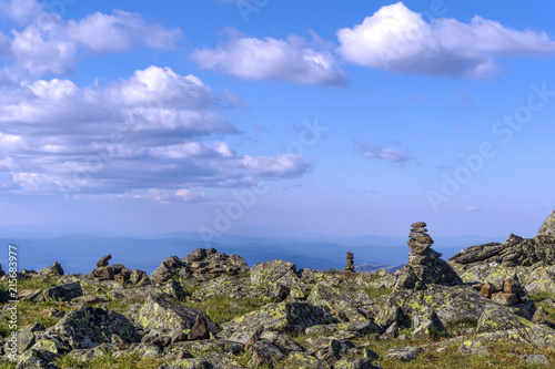 bright landscape of a high-altitude plateau with folded travelers pyramids cairns of stones under a blue sky with clouds photo