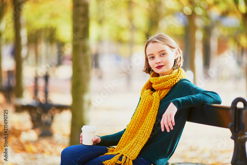 Happy young girl in yellow scarf walking in autumn park