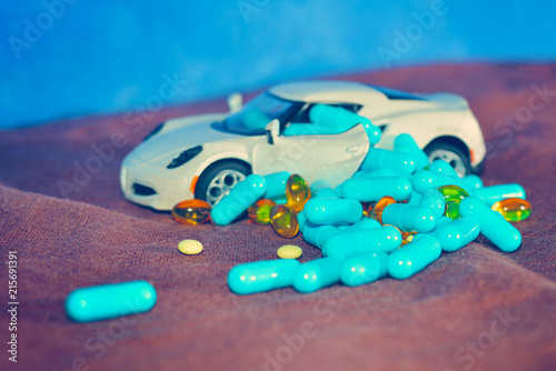 A child's white machine unloads blue capsules and different tablets on a brown surface on a blue background. The concept of pharmacological industry. photo