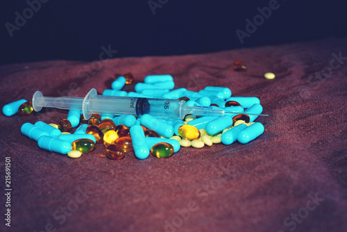 A hand in a blue medical glove holds medications and pills of different colors on a black background. The concept of pharmacological industry. photo