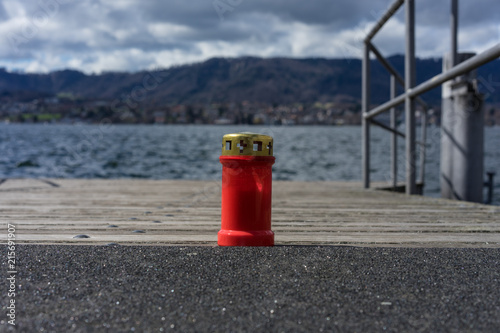 red candle on lake pier with water background, concept photo