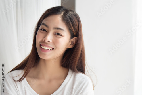happy smiling girl; portrait of positive relaxed happy smiling asian woman smiles in indoor home environment; young adult asian persian woman or asian middle east woman model