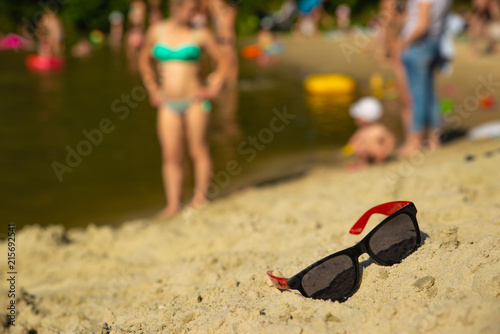 sunglasses in sand at beach. blurred people on background. summer time
