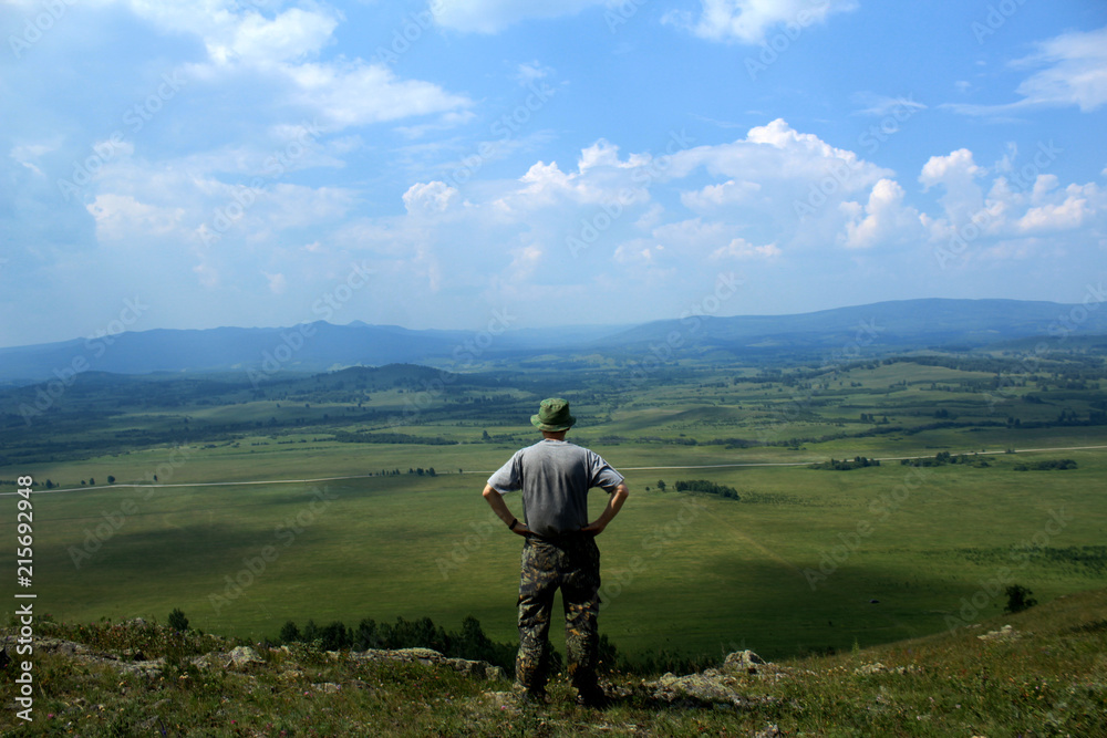 A man stands on a mountain and looks at the valley. HDR.
