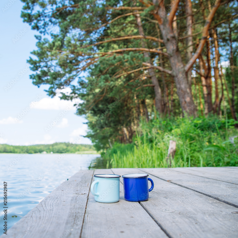 two metal cups with tea. river on background. summer time concept two metal cups with tea. river on background. summer time concept