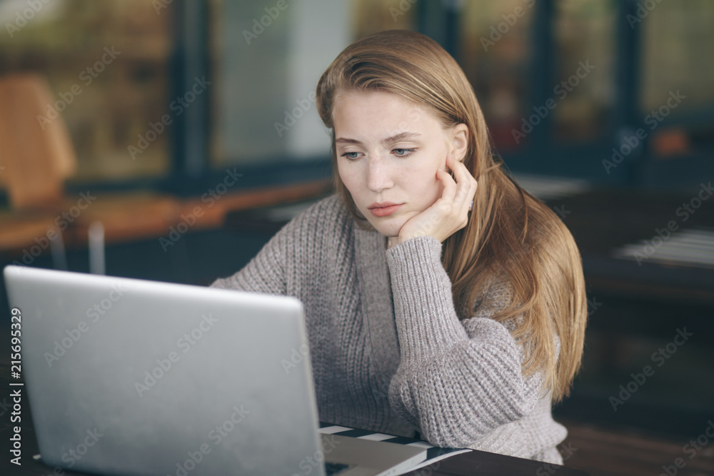 Thoughtful concept. Woman working on a computer at a cafe while gazing through the window glass. Thoughtful concept. Woman working on a computer at a cafe while gazing through the window glass.