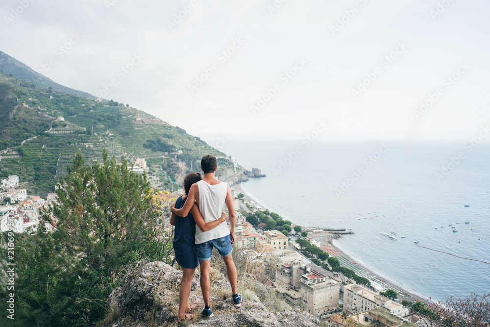 couple standing at the mountains and look down