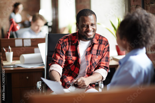 Smiling African businessman in casual clothes conducting the interview with woman at office