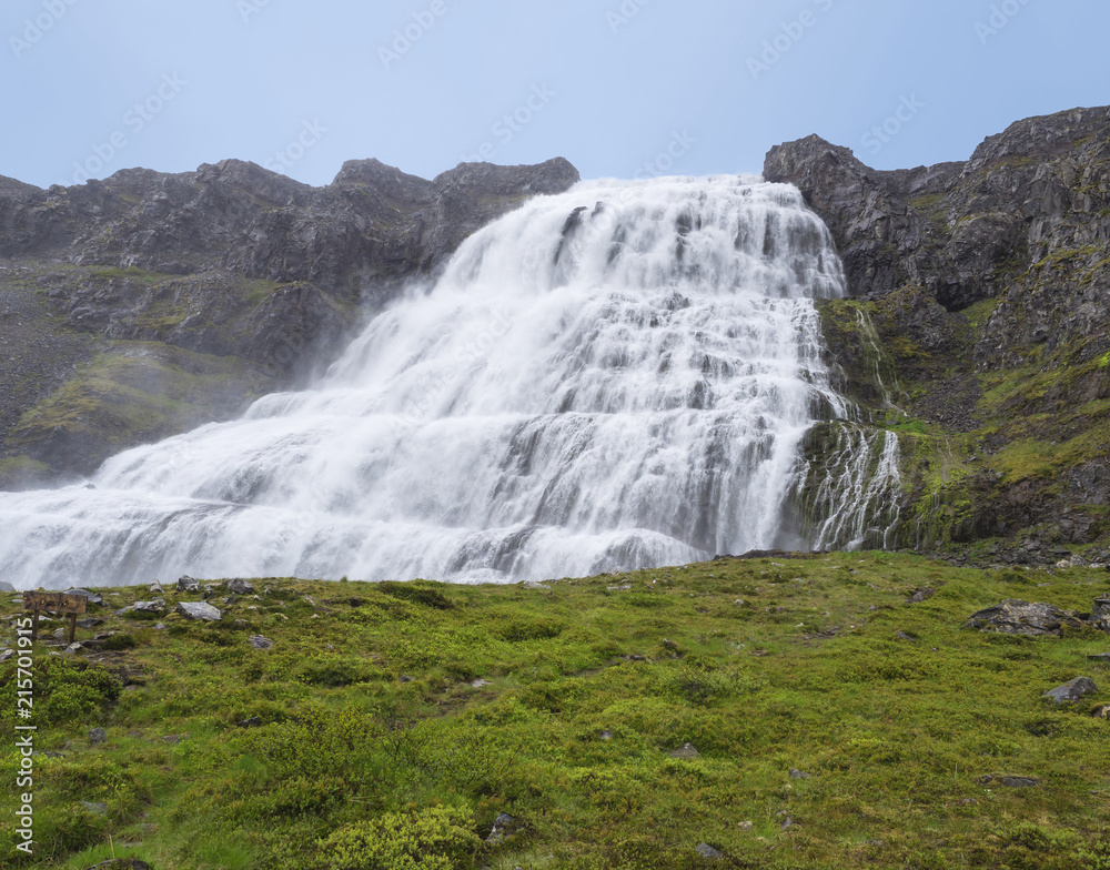 Fototapeta premium Dynjandi waterfall, biggest in west fjords of Iceland in summer, rock, green grass and blue sky background