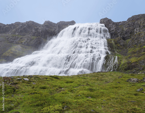 Dynjandi waterfall  biggest in west fjords of Iceland in summer  rock  green grass and blue sky background