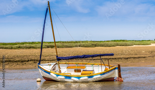 White sail boat beached at low tide, Burnham Overy Staithe, Norfolk