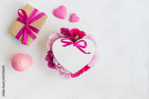 Frame with pink flowers with gift box on light background