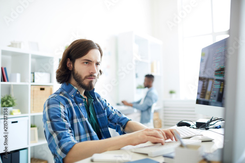 Quadro em tela Serious concentrated hipster young bearded computer programmer working with two