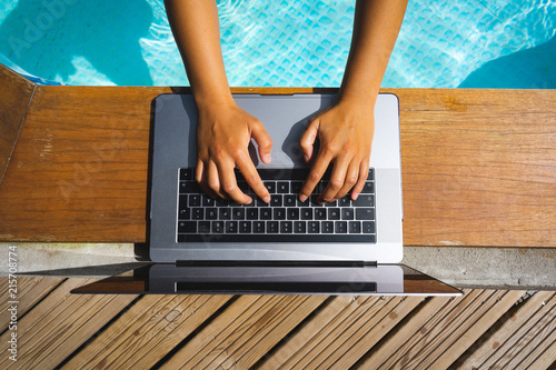 Quadro em tela Screen mockup of laptop that a woman is using at the pool on vacation - work anywhere and internet work concept
