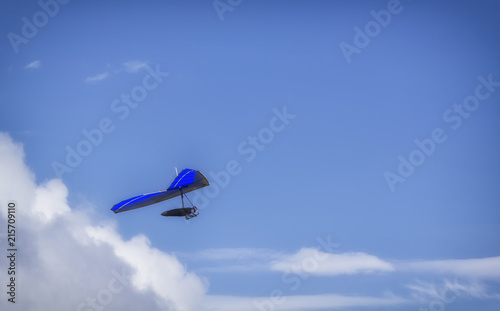 Hang Glider flying in the sky on a sunny bright blue day
