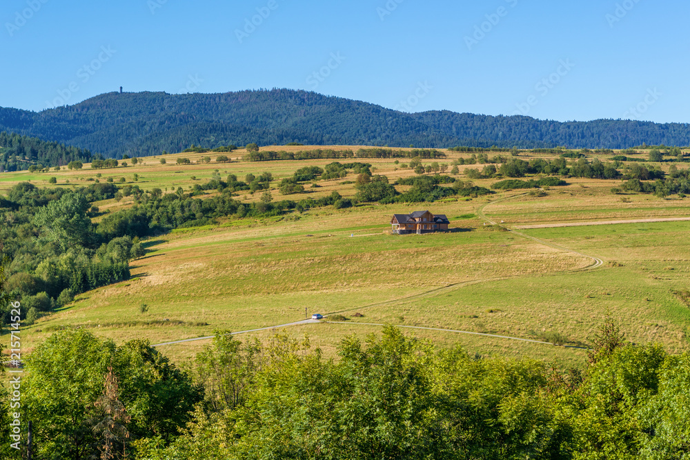 Picturesque rural landscape with house on fields in summer day. Pieniny mountains, Poland.