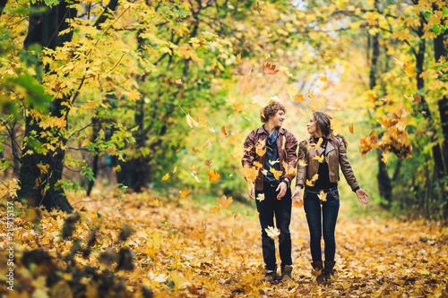 loving couple in an autumn park. Man and woman cheerfully throw yellow leaves up.