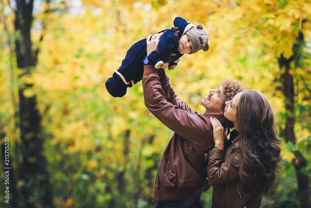 Young happy family in autumn in park. Father joyfully throws his son up. Young happy family in autumn in park. Father joyfully throws his son up.
