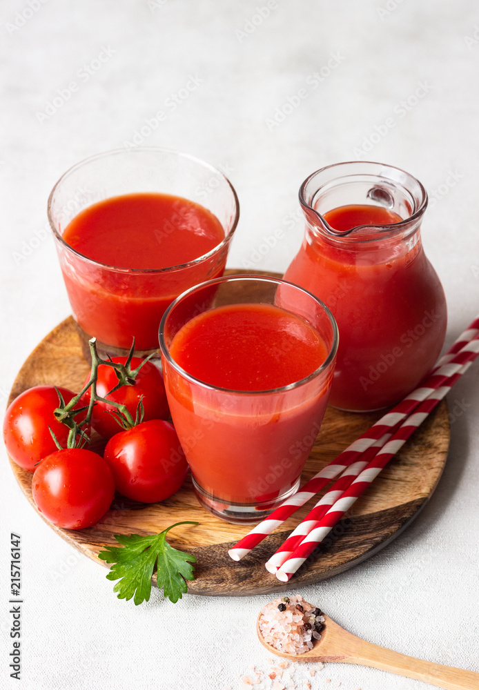 Tomato juice with fresh tomatoes, parsley, sea salt and pepper on light grey background. Vegetable drink.