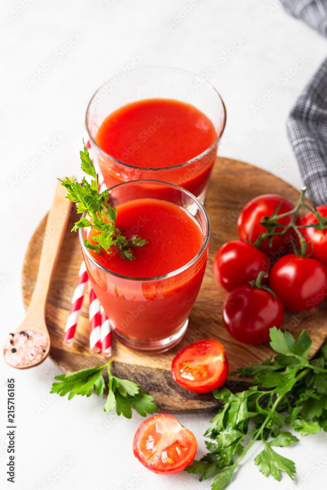 Tomato juice with fresh tomatoes, parsley, sea salt and pepper on light grey background. Vegetable drink. Tomato juice with fresh tomatoes, parsley, sea salt and pepper on light grey background. Vegetable drink.