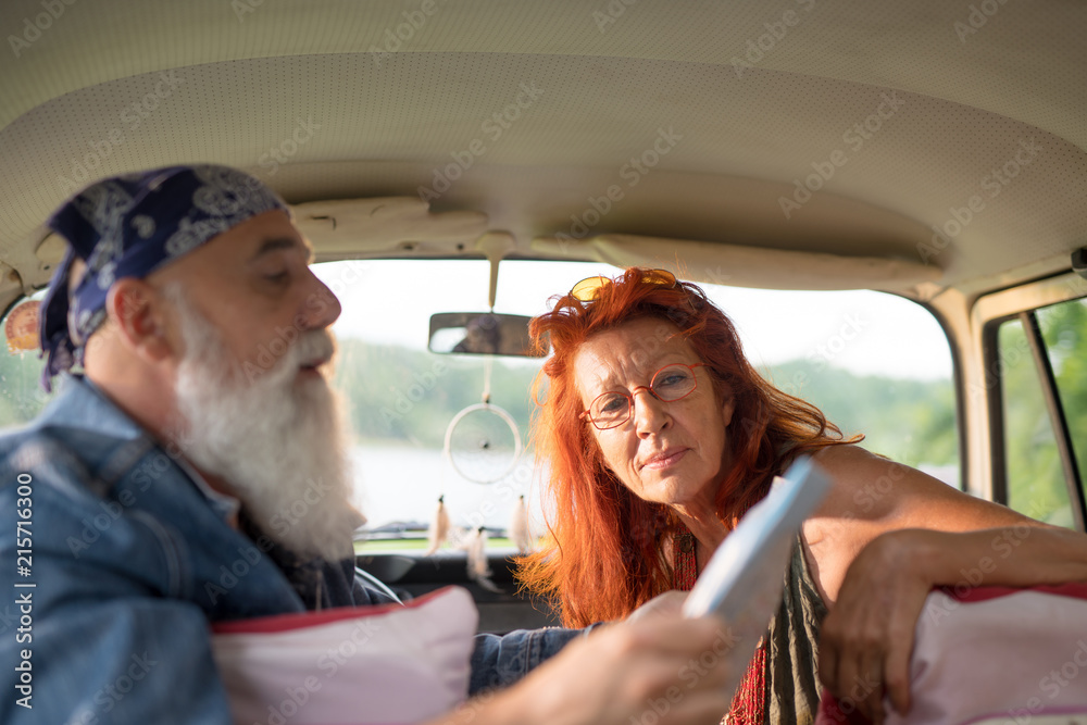 A hipster senior couple on vacation in a van, looking at a ma A hipster senior couple on vacation in a van, looking at a ma